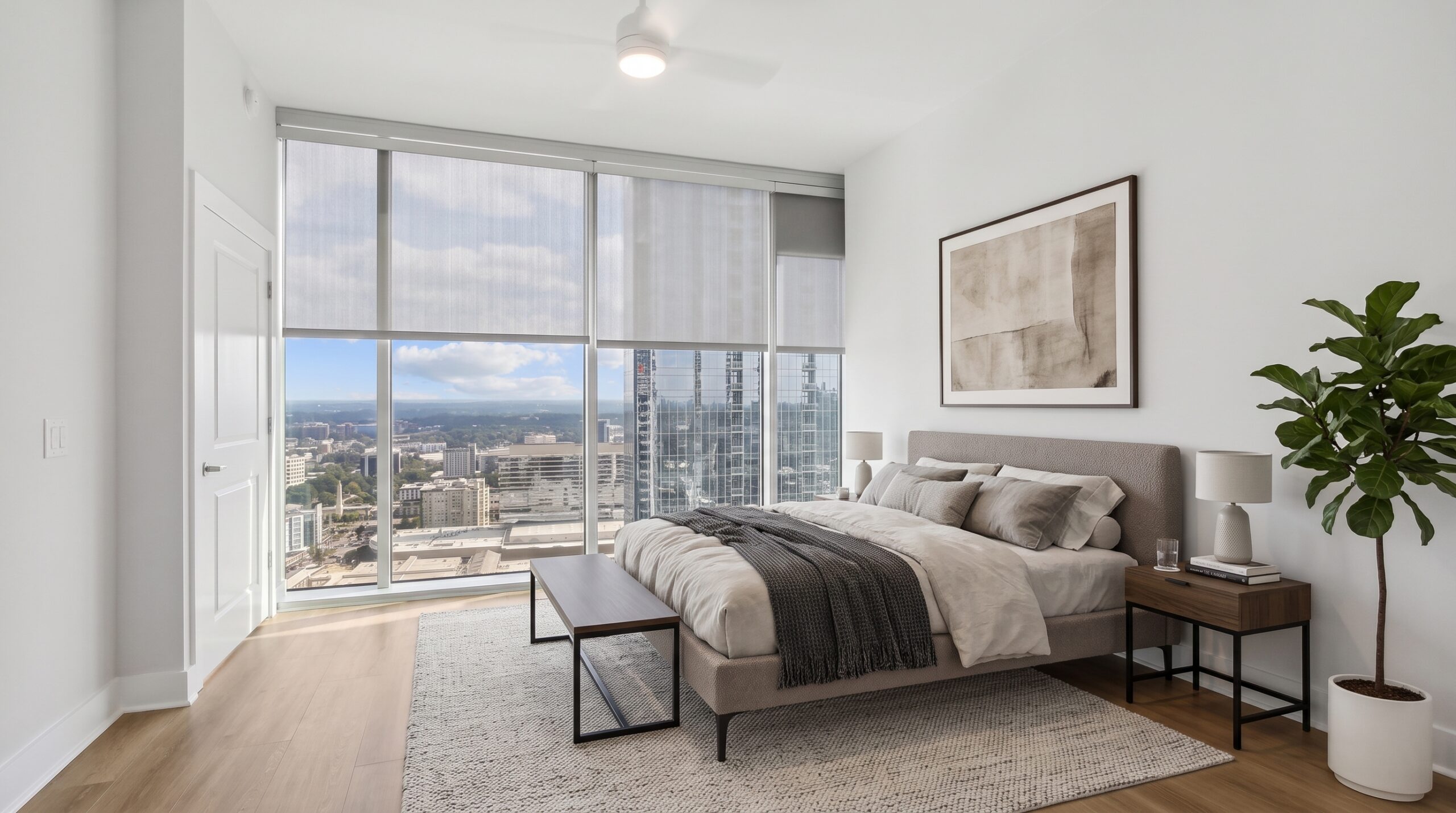 Modern bedroom with a queen-sized bed, floor-to-ceiling windows overlooking a city skyline, and a potted plant.