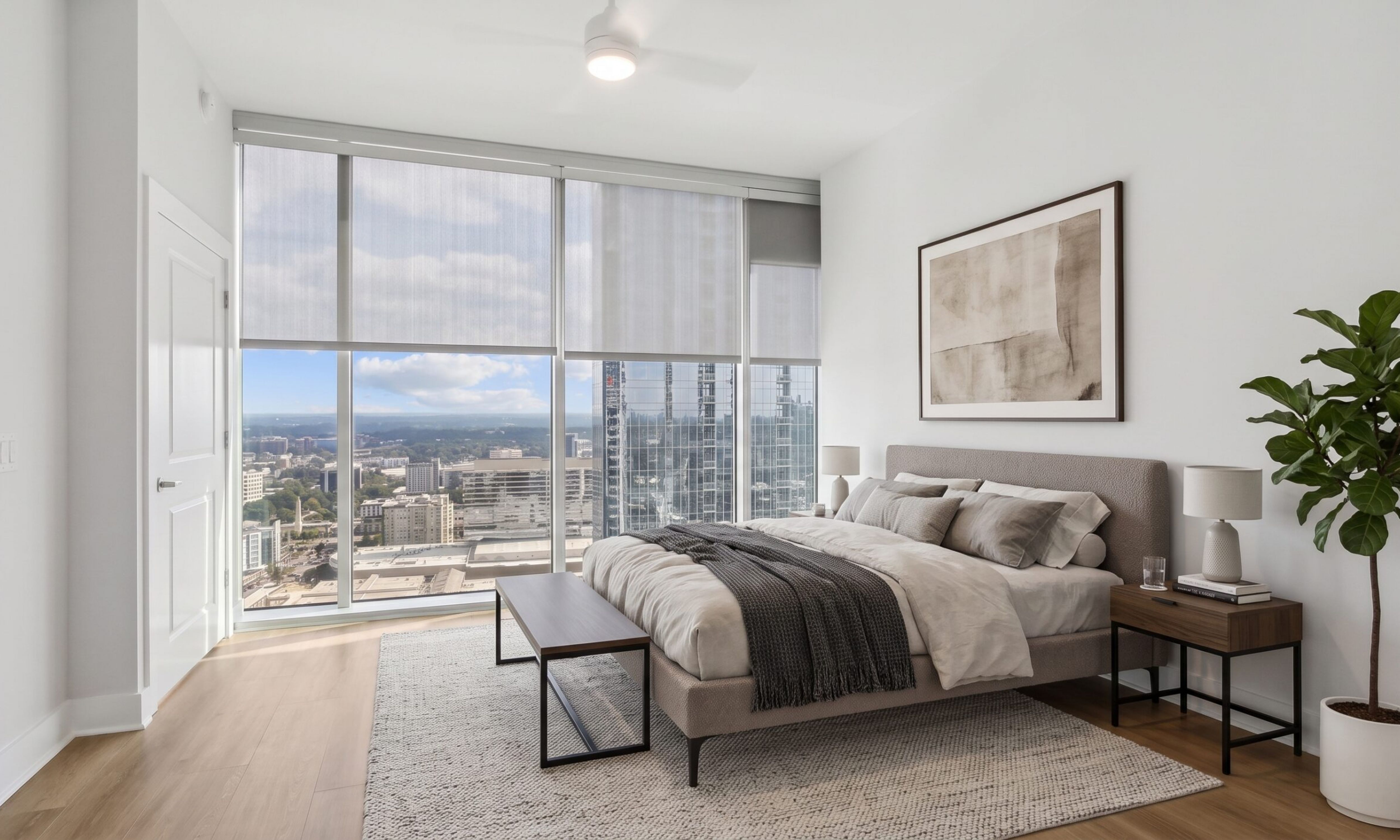 Modern bedroom with a queen-sized bed, floor-to-ceiling windows overlooking a city skyline, and a potted plant.