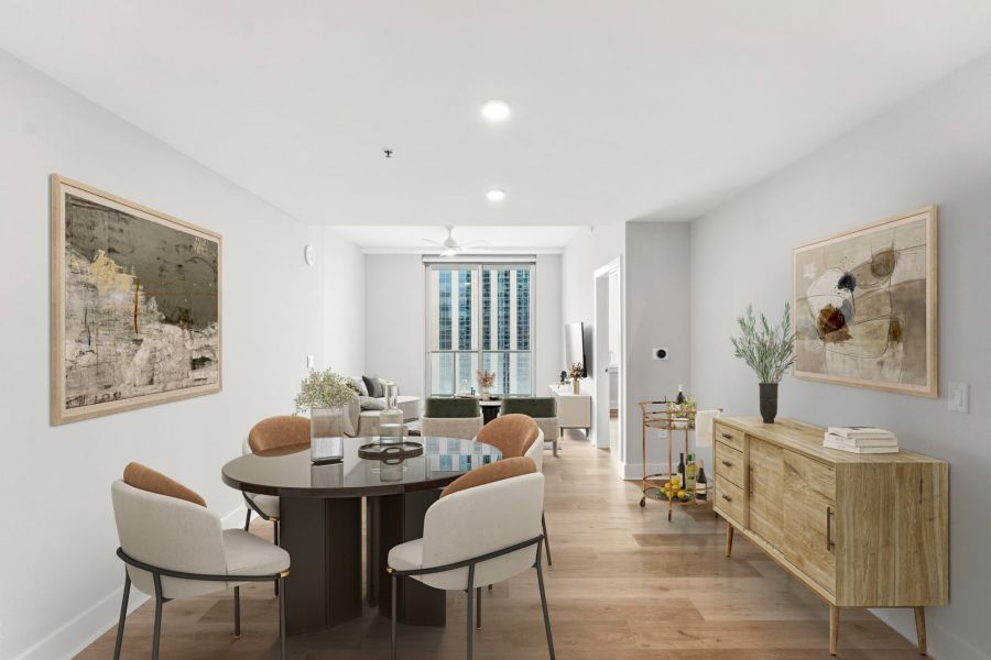 Modern open-plan living and dining area with light wood floors, contemporary furniture, and large window with city view.